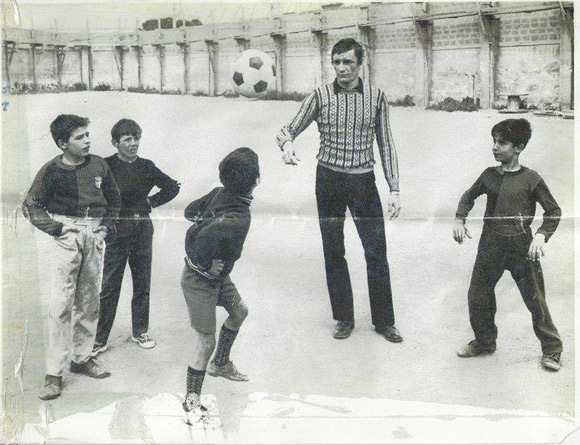foto di Gigi Riva che gioca a pallone con alcuni bambini nel quartiere Marina